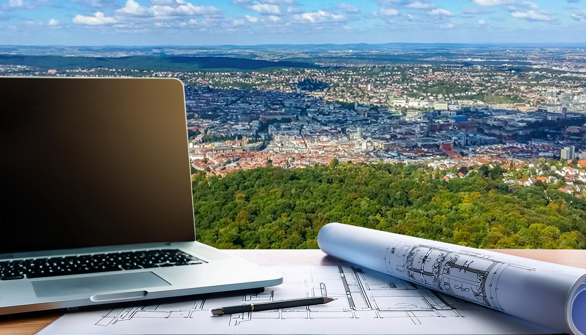 Im Vordergrund ist ein Laptop mit Bauplänen un im Hintergrund ist die Stadt Stuttgart zu sehen.